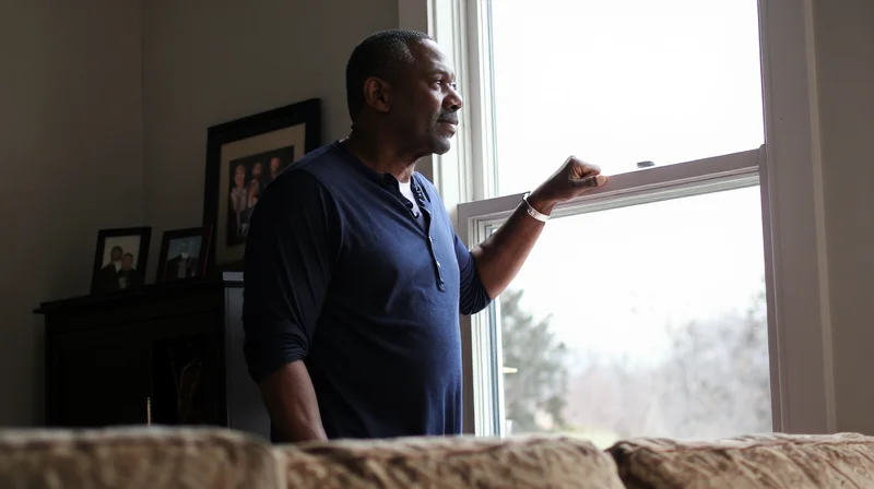 A Black man in his 60s standing at a window lost in thought, reflecting the grief and emotional complexity of dating in your 60s after loss